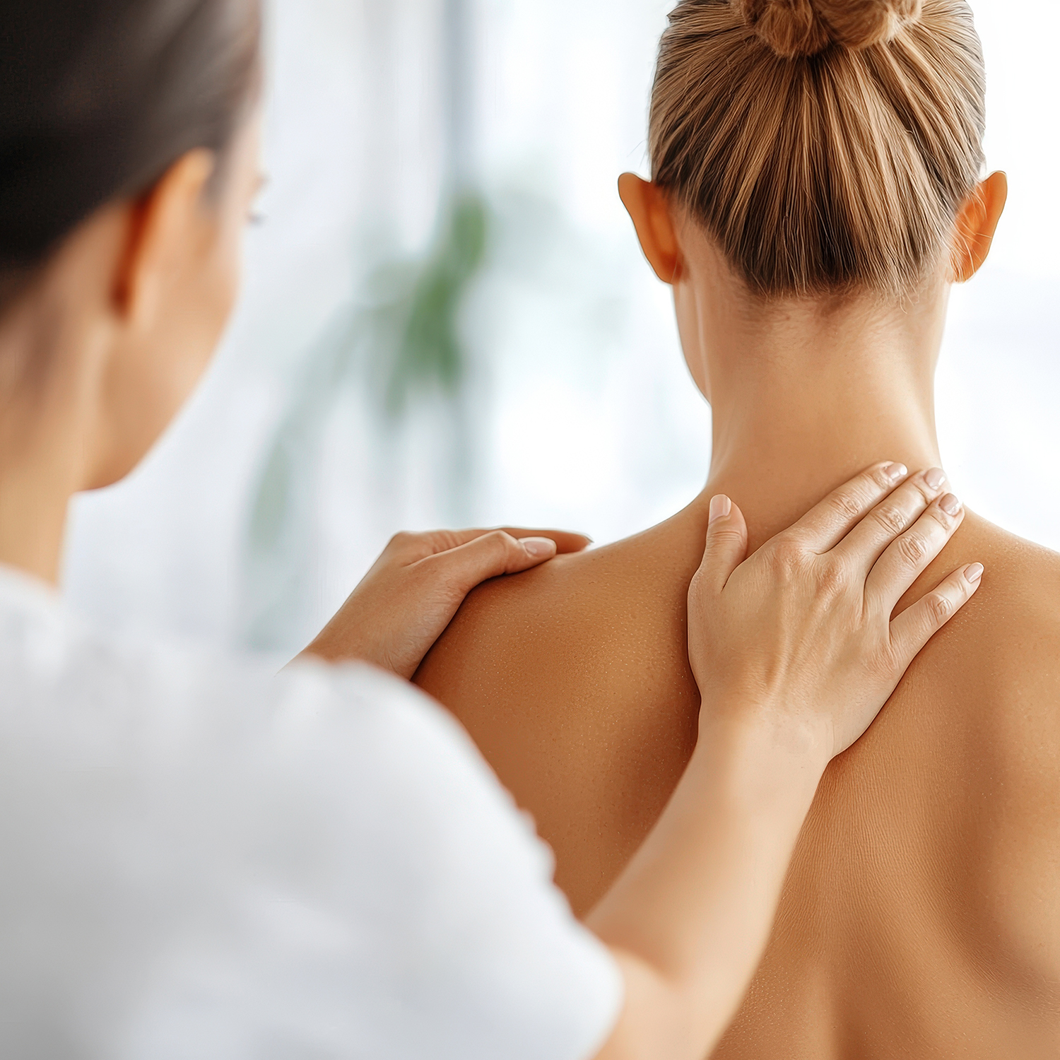 A physiotherapist guiding a patient in shoulder blade pinching exercises.